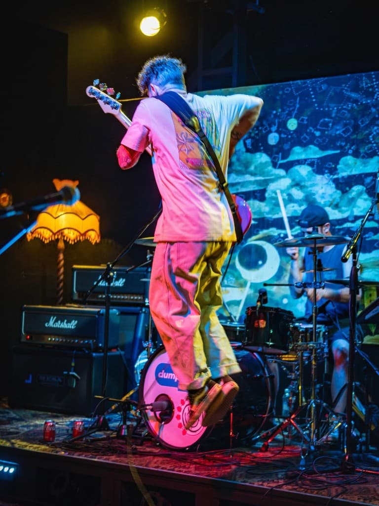 Bassist jumping mid-performance on stage with Marshall amps behind